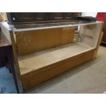 A 6' 1" mid 20th Century mixed wood shop counter with glazed top and front, sliding doors to rear