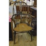 A Georgian style elm Windsor comb back elbow chair with wheel splat and solid seat, set on ring