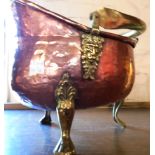 A hammered copper coal helmet pattern planter with brass swing handle and paw feet