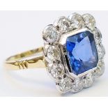 A marked 18ct. yellow metal ring, set with central canted square sapphire (3.20ct.) within a
