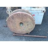 A 25" diameter sandstone grinding wheel with handle and brackets