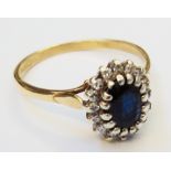 An 18ct. gold ring, set with central dark oval sapphire within a diamond encrusted border