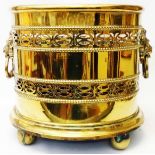 A Georgian style oval brass log bucket in the form of a wine cooler with flanking lion mask ring