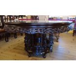 A 5' diameter Chinese stained rosewood dining table with ornate pierced and carved frieze