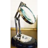 An adjustable table magnifier with silver plated finish and socle base