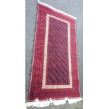 A Turkish Baluch wool rug with knotted sides, repeat motif, black and gold on a red ground - 3'