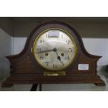 A 1930's stained oak cased mantel clock with presentation plaque and eight day gong striking