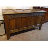 A 4' 3" antique oak four panel coffer with decorative carved frieze, set on reeded block feet