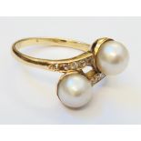 An unmarked high carat yellow metal cross-over ring, set with two cultured pearls and tiny diamonds