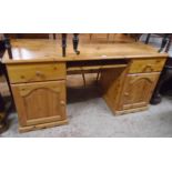 A 4' 11" modern pine kneehole desk with central slide and flanking short drawers with panelled