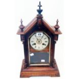 An American wood grained cased shelf clock with turned finials, visible pendulum and gong striking