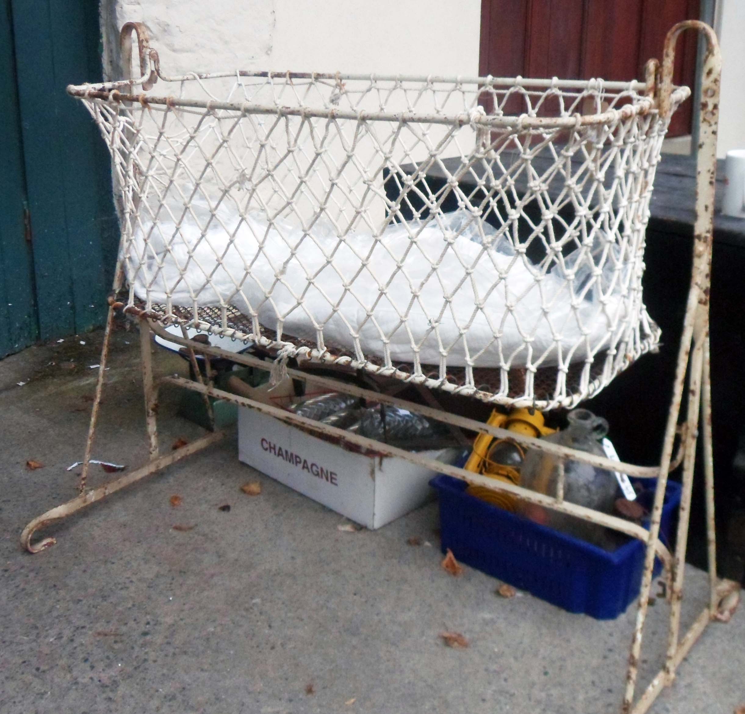 A vintage metal and rope mesh rocking crib