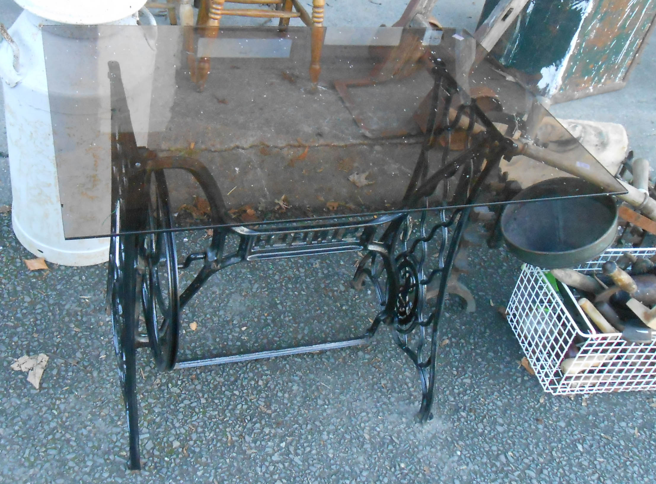 A Singer treadle base with smoked glass top - as a garden table