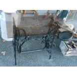 A Singer treadle base with smoked glass top - as a garden table