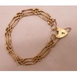 An unmarked yellow metal gate-link bracelet with marked 9ct. heart shaped padlock