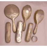 A silver backed four piece hand mirror and brush set - sold with two other silver backed brushes and