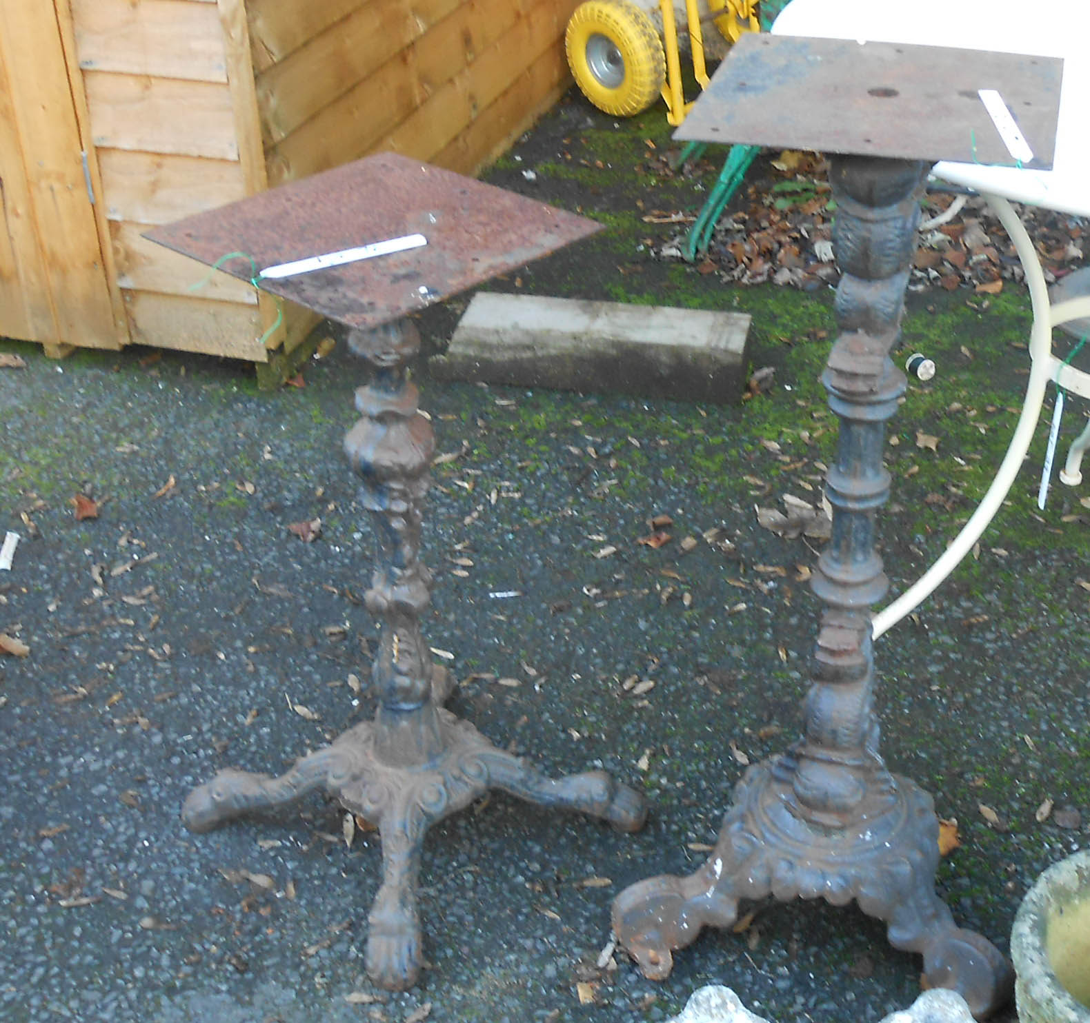 Two modern painted cast iron public house table pedestals with ornate decoration, one set on tripod,