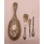 A silver backed hair brush, shoe horn, button hook and tweezers