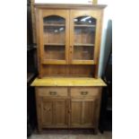 A 3' 6" 20th Century waxed pine two part dresser with glazed cabinet over a base with two short