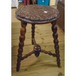 An oak stool with carved seat and turned tripod base