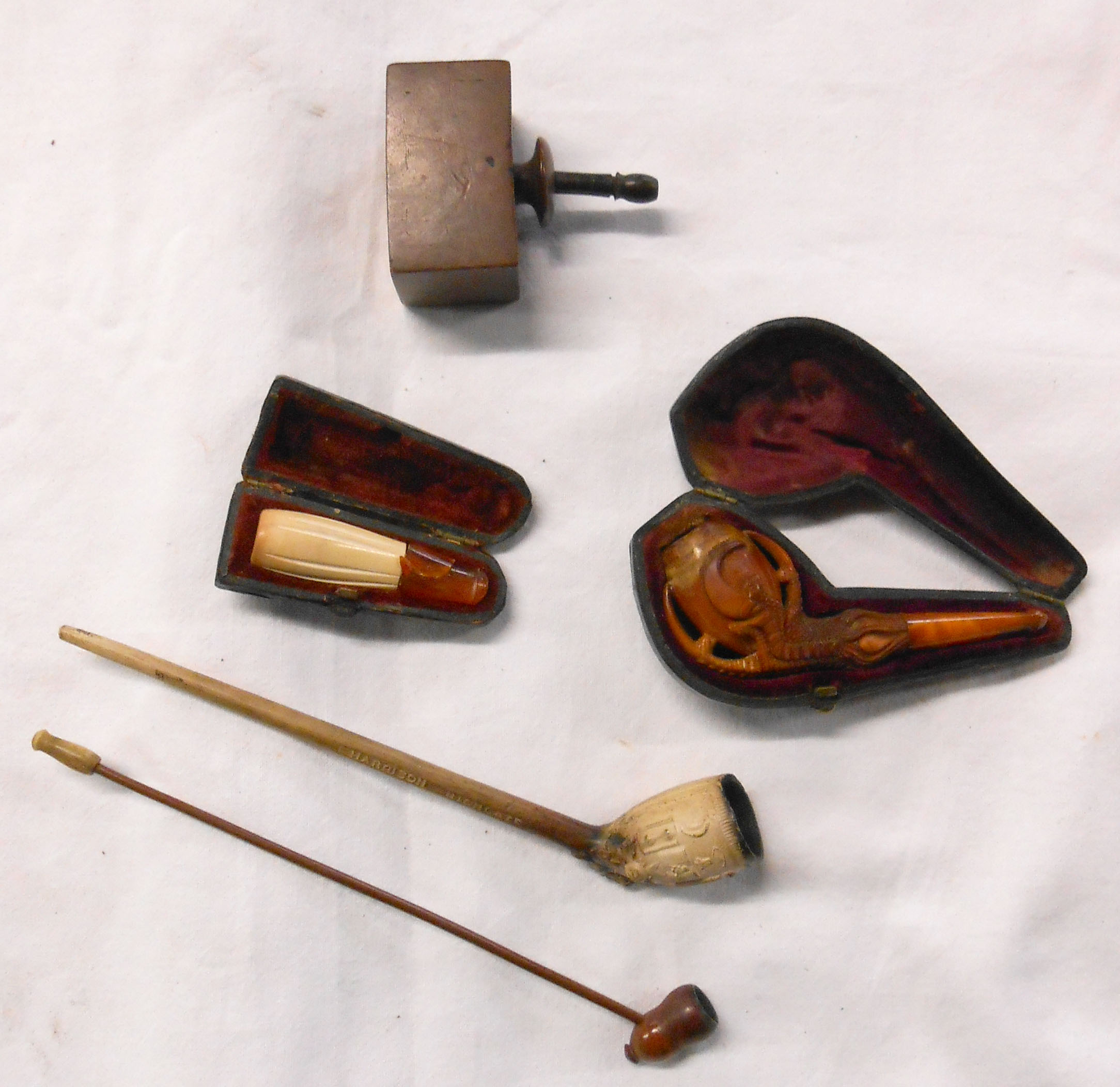 A small collection of antique pipes, comprising a cased meerschaum claw with amber mouthpiece,