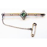 An early 20th Century 9ct. gold bar brooch with open set central peridot, six seed pearls and safety