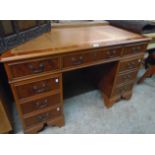 A 4' reproduction yew twin pedestal desk with brown leatherette inset top, three frieze drawers