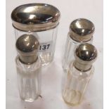 Four dressing table bottles with silver plated tops