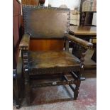 A stained oak framed elbow chair with studded brown leather upholstery to back, armrests and seat,