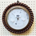 A 9 1/2" diameter 19th Century carved oak rope twist bordered aneroid wall barometer by Christie &
