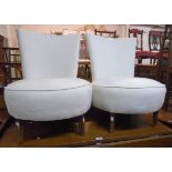 A pair of retro boudoir chairs with curved backs and deep circular seats upholstered in white shot