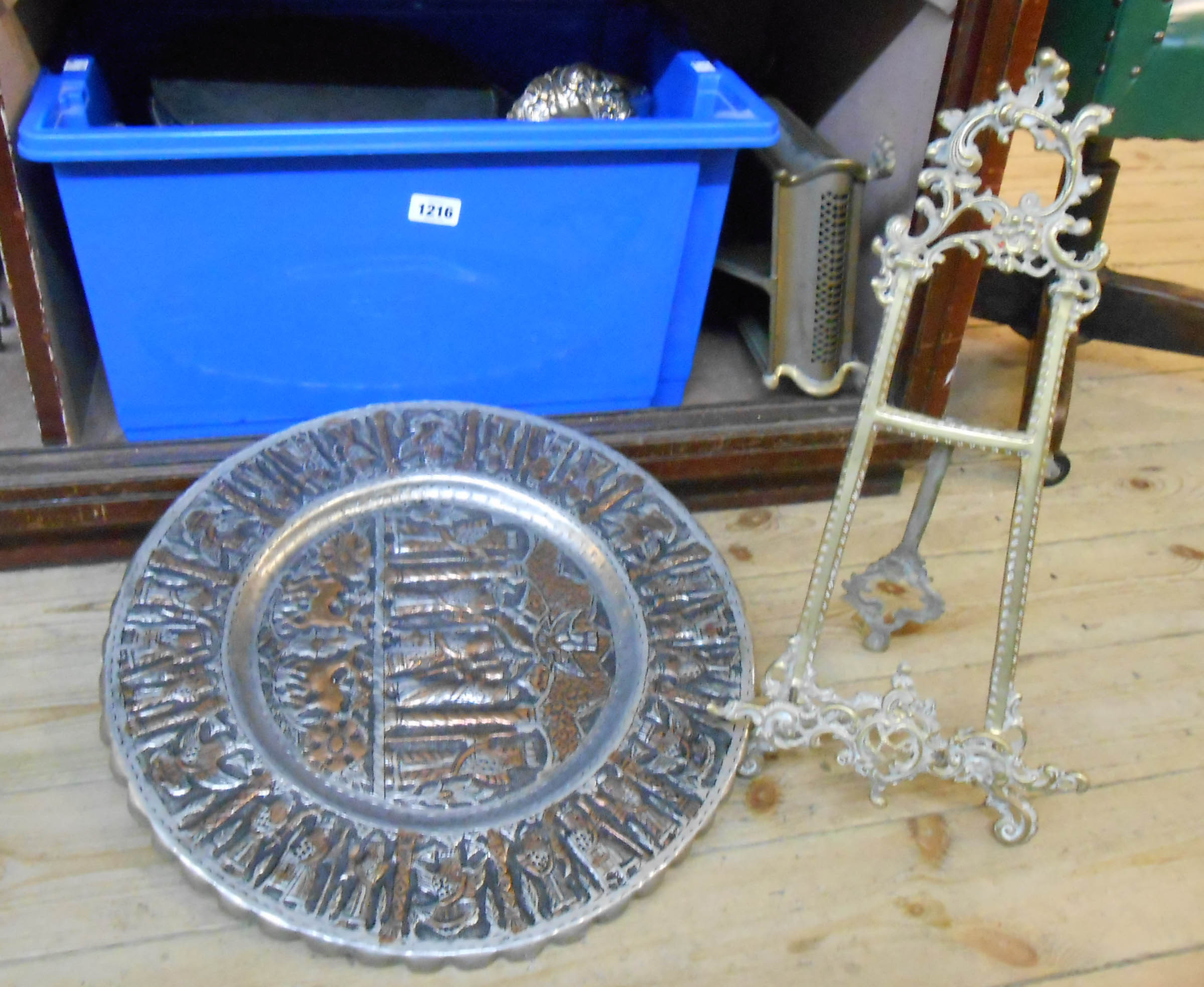 A crate containing assorted metalware, including brass easel, tray, trivet, etc.