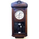 An early 20th Century oak cased wall clock with visible pendulum and spring driven chiming movement