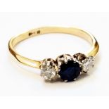 An 18ct. gold ring set with central sapphire flanked by two small diamonds