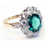 A marked 18ct. yellow metal ring, set with central 1.7ct. oval emerald within a diamond encrusted