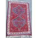 A hand knotted Persian rug with uniting blue geometric medallions on red ground depicting flowers