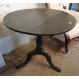 A 30 1/2" diameter late Georgian oak tilt-top table, set on turned pillar and tripod base with pad