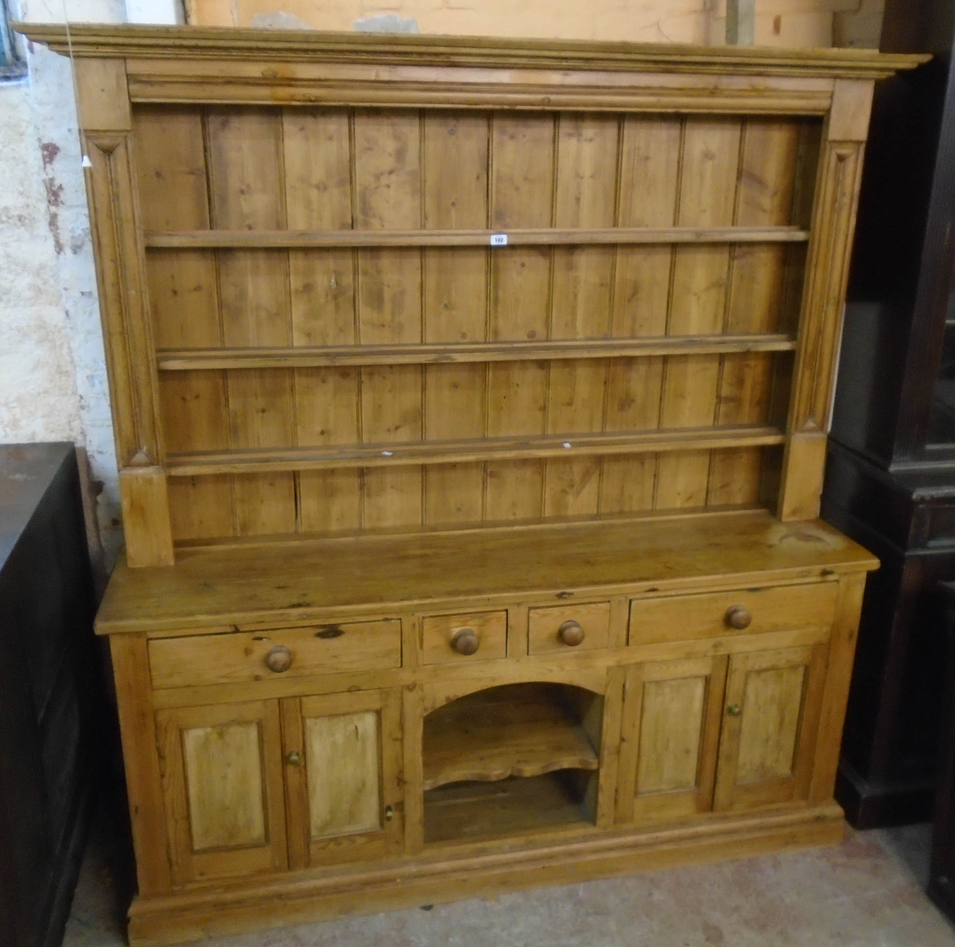 A 6' 2" waxed pine two part dresser with moulded cornice and flanking decoration to three shelf open