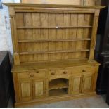 A 6' 2" waxed pine two part dresser with moulded cornice and flanking decoration to three shelf open