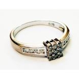An 18ct. white gold ring, set with nine small diamonds to central square panel and with further
