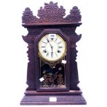 A late 19th Century American stained wood gingerbread shelf clock with printed glass door, visible