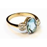 A marked 18ct. yellow metal ring, set with large central oval aquamarine flanked by two diamonds