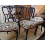 A set of four early 20th Century stained wood framed dining chairs with decorative pierced
