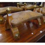 A pair of 20th Century camel saddle stools with brass decoration and tooled leather swab seats