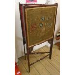 An early 20th Century stained walnut two fold draught screen with woolwork panels and pierced