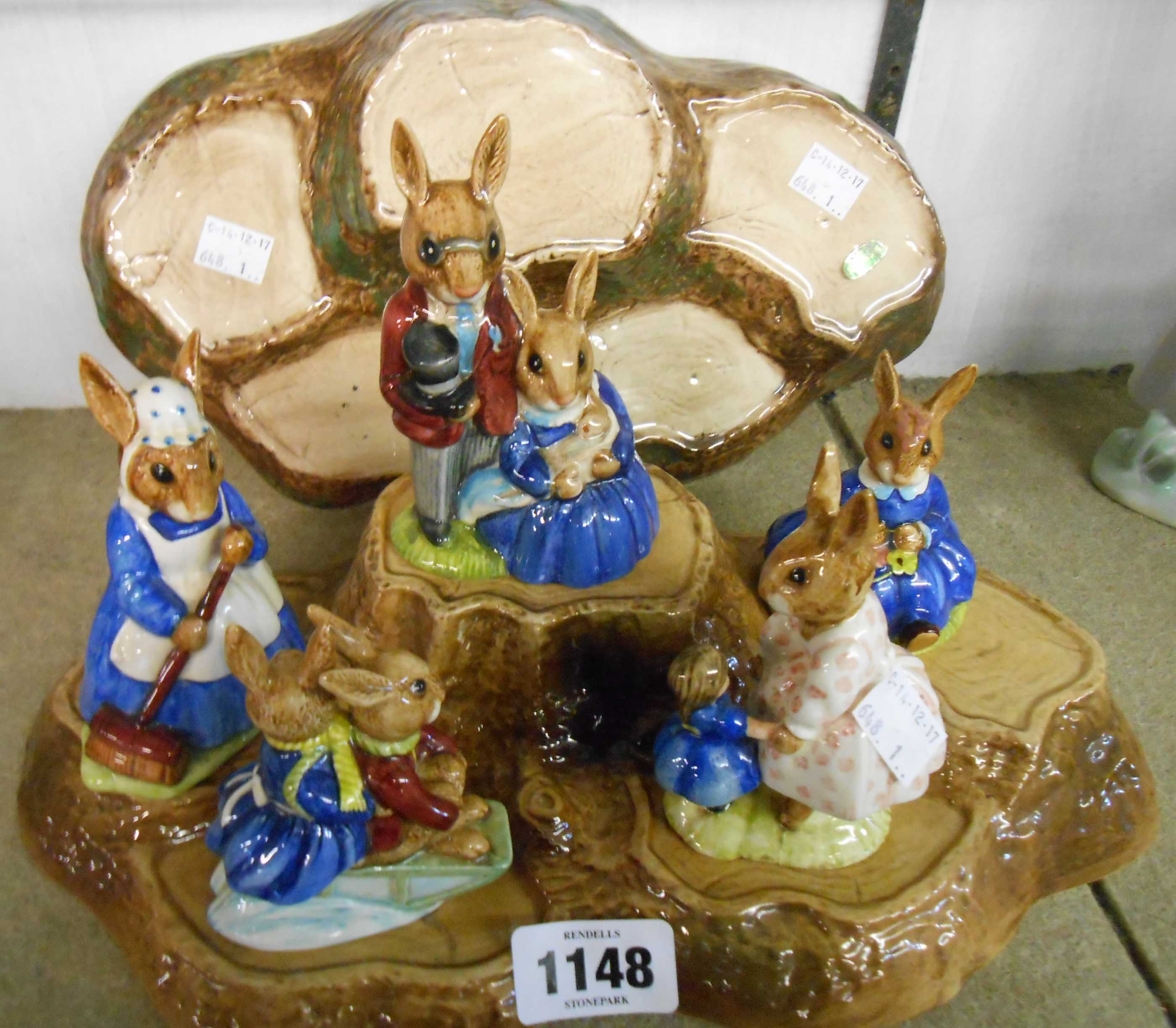 Five Royal Doulton Bunnykins figures on a tree trunk pattern stand and a Beswick stand similar