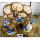 Five Royal Doulton Bunnykins figures on a tree trunk pattern stand and a Beswick stand similar