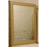 A modern buff painted and parcel gilt framed bevelled oblong wall mirror with repeat foliate border