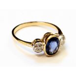 A marked 18ct. yellow metal ring, set with central oval sapphire and flanking diamonds