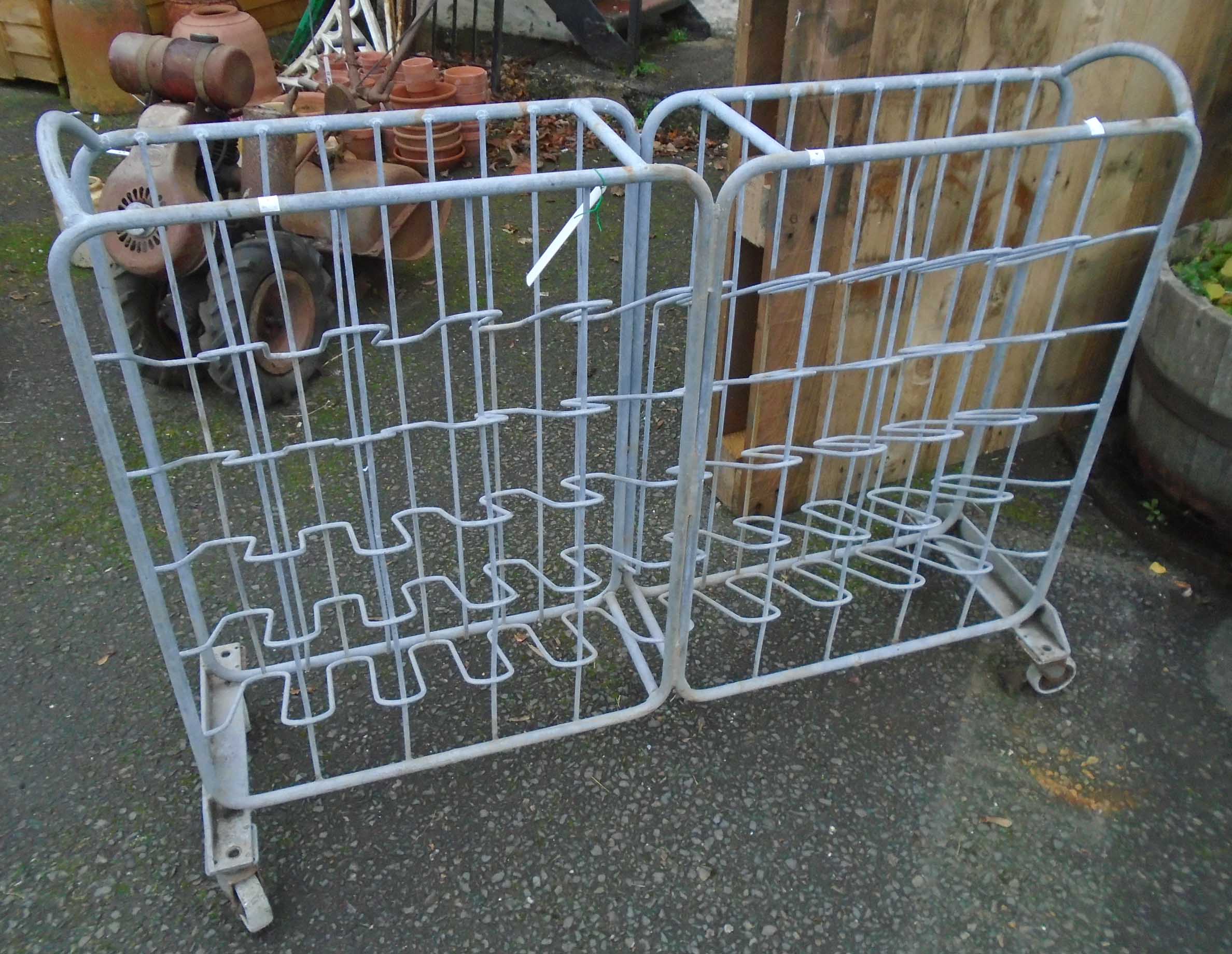 An industrial galvanised tubular metal and wire framed bottle rack, set on rubber casters